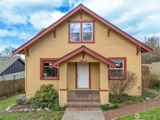 bungalow-style house featuring brick siding and fence