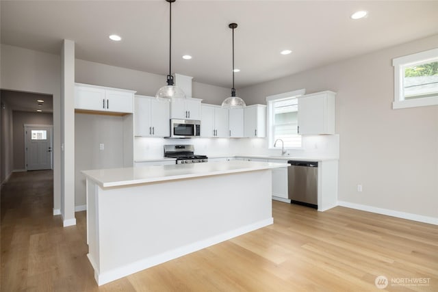 804 Parkland Loop, Sedro Woolley, WA 98284 - kitchen with stainless steel appliances, white cabinets, light wood-type flooring, a kitchen island, and light countertops