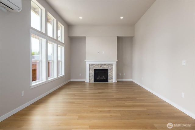 804 Parkland Loop, Sedro Woolley, WA 98284 - unfurnished living room with a wall mounted AC, light wood-style flooring, baseboards, recessed lighting, and a stone fireplace