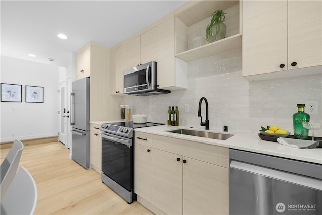 kitchen with light countertops, appliances with stainless steel finishes, light wood-type flooring, and a sink