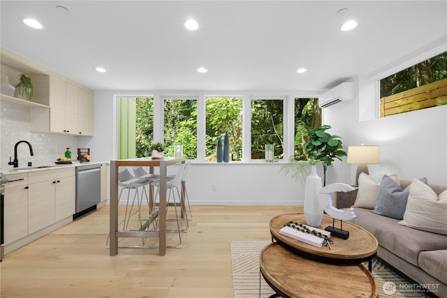 interior space with a sink, stainless steel dishwasher, light wood finished floors, a wall mounted air conditioner, and tasteful backsplash