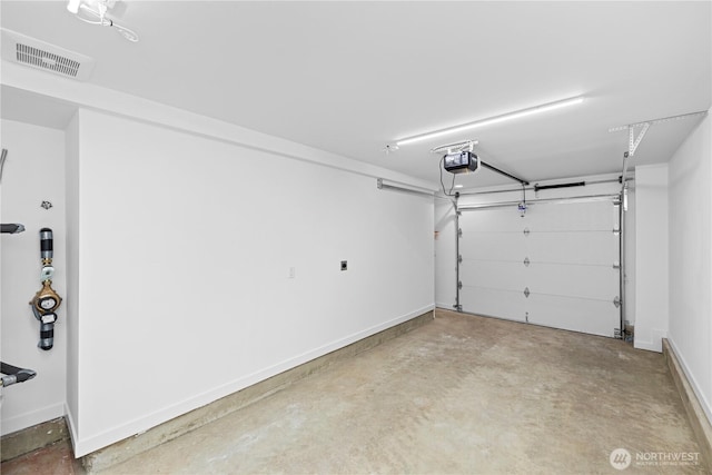 garage featuring a garage door opener, visible vents, and baseboards