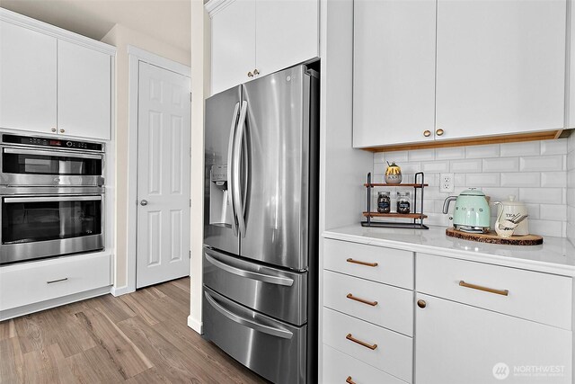 15132 Tyee Dr E, Bonney Lake, WA 98391 - kitchen featuring light wood-style flooring, tasteful backsplash, white cabinetry, stainless steel appliances, and light countertops