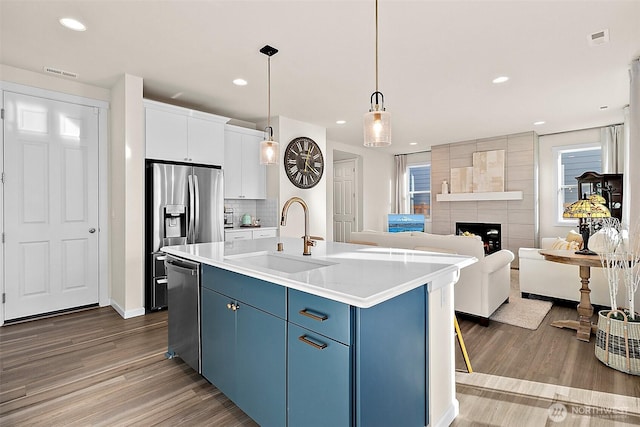 15132 Tyee Dr E, Bonney Lake, WA 98391 - kitchen with visible vents, blue cabinetry, stainless steel appliances, a sink, and a tiled fireplace
