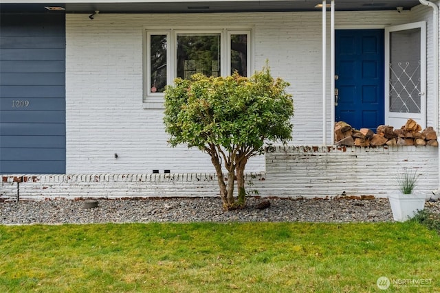 view of home's exterior with brick siding, a lawn, and a porch