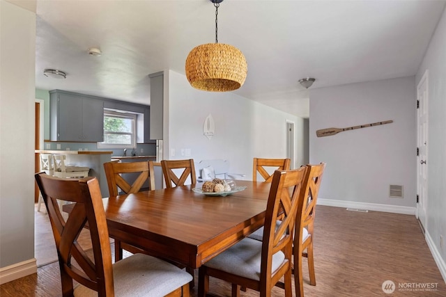 dining space featuring wood finished floors, visible vents, and baseboards