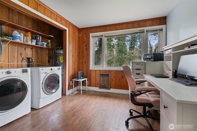 washroom with wooden walls, washing machine and dryer, laundry area, wood finished floors, and heating unit