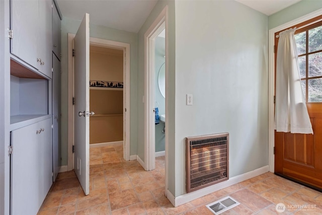 bathroom with heating unit, baseboards, and visible vents