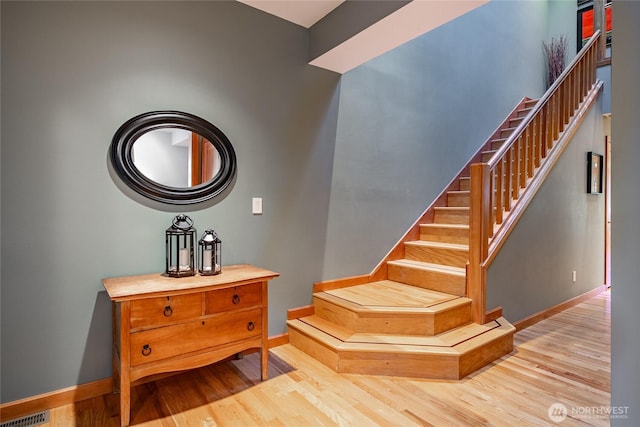 stairway featuring visible vents, baseboards, and wood finished floors