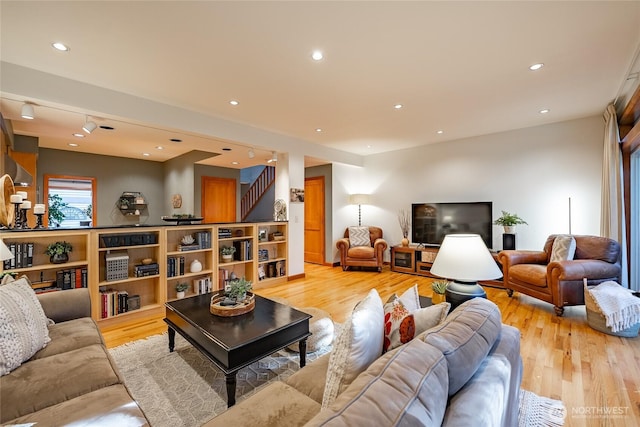 living area with recessed lighting, light wood-style floors, and stairs