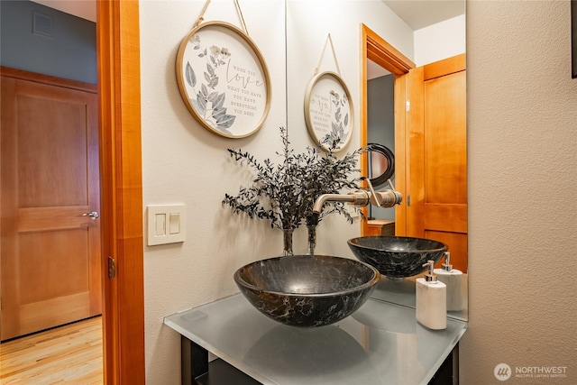 interior space with visible vents, wood finished floors, vanity, and a textured wall