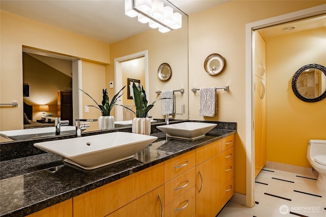 full bathroom with double vanity, toilet, and a sink