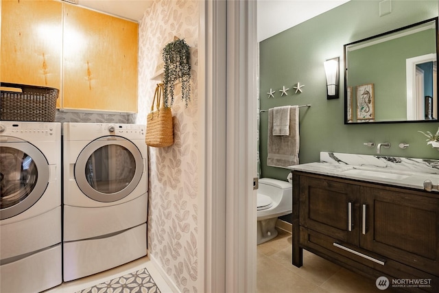 washroom featuring a sink, cabinet space, washing machine and dryer, and light tile patterned floors