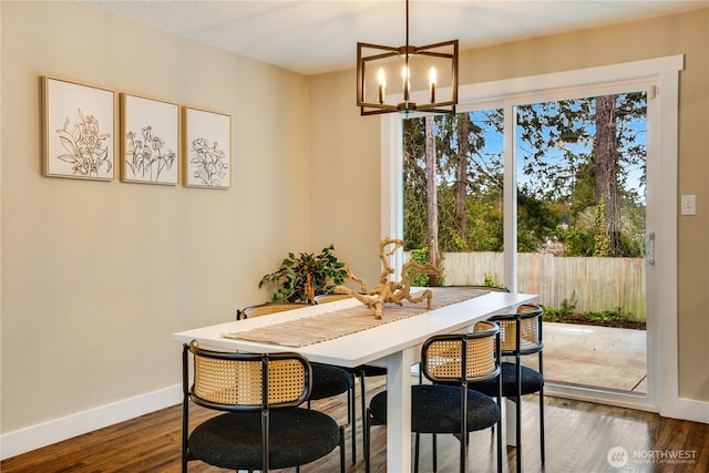 dining area featuring dark wood finished floors, a notable chandelier, a healthy amount of sunlight, and baseboards