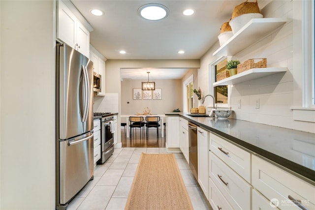 kitchen with a sink, dark countertops, appliances with stainless steel finishes, and white cabinets