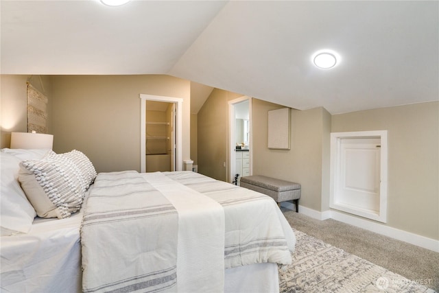 carpeted bedroom featuring connected bathroom, baseboards, and vaulted ceiling