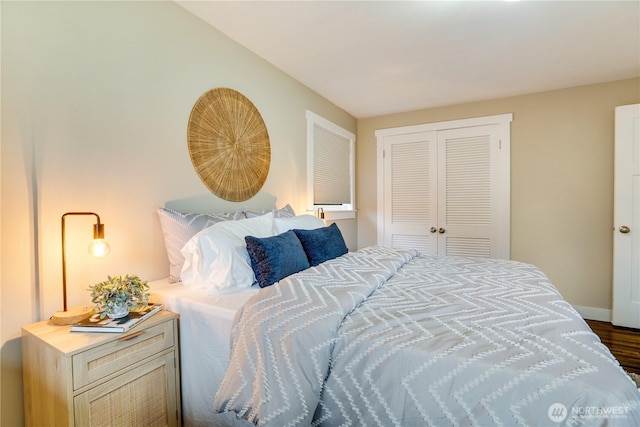 bedroom featuring a closet, baseboards, and dark wood-style flooring