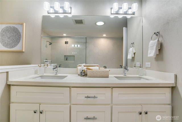 full bathroom with a sink, visible vents, a stall shower, and double vanity