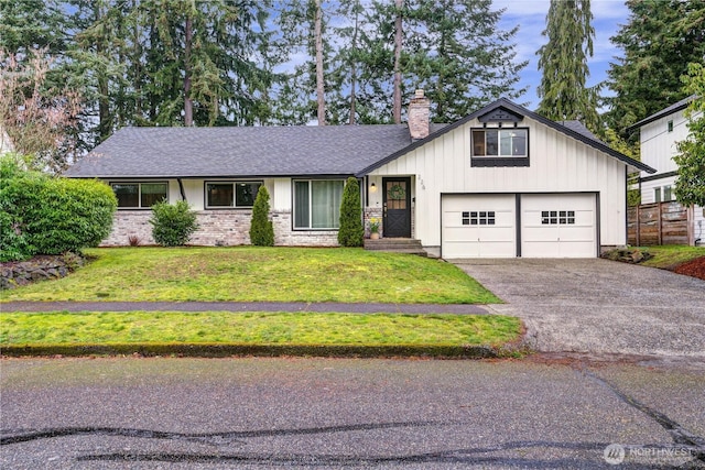 view of front of house featuring a front lawn, aphalt driveway, board and batten siding, a shingled roof, and a chimney