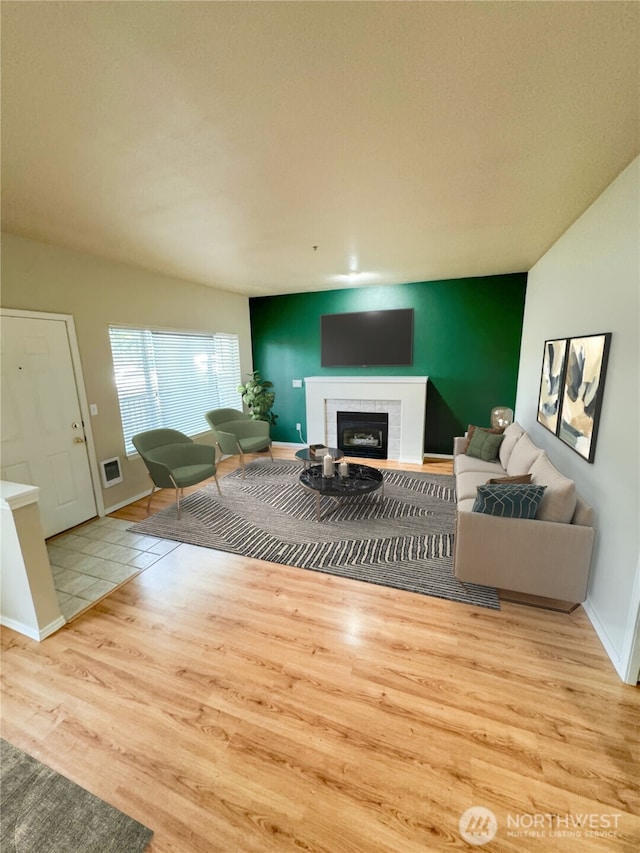 living area featuring a fireplace, baseboards, and wood finished floors