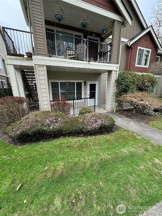 exterior space featuring a balcony, stairs, a lawn, and board and batten siding