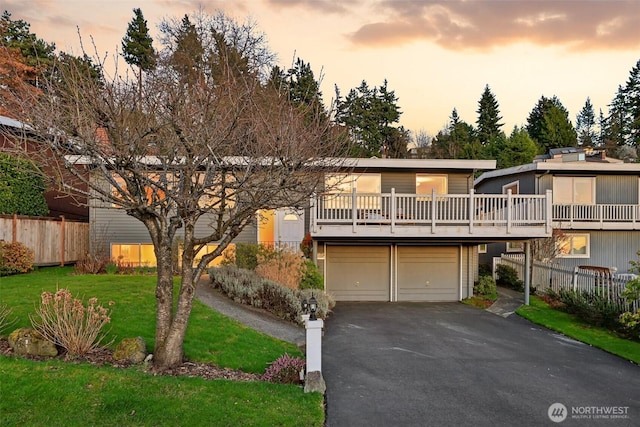 view of front of home with a lawn, an attached garage, driveway, and fence