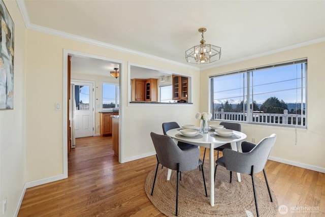 dining area with baseboards, a healthy amount of sunlight, wood finished floors, and ornamental molding