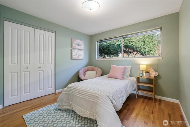 bedroom featuring a closet, multiple windows, baseboards, and wood finished floors