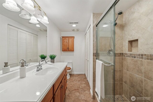 full bath with visible vents, toilet, a stall shower, and vanity