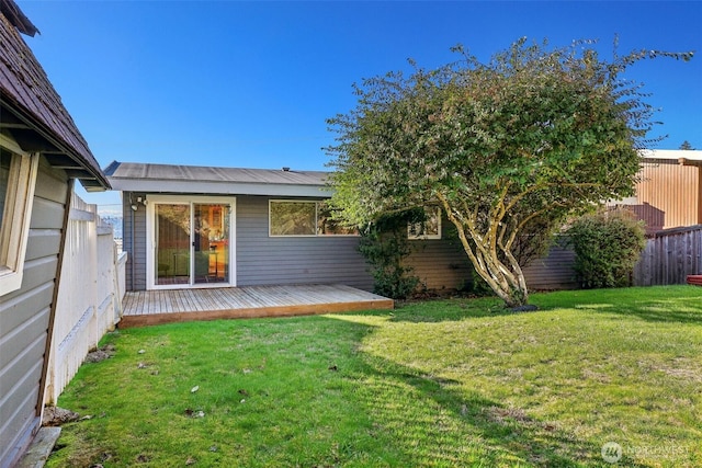 rear view of house featuring metal roof, a lawn, a wooden deck, and fence