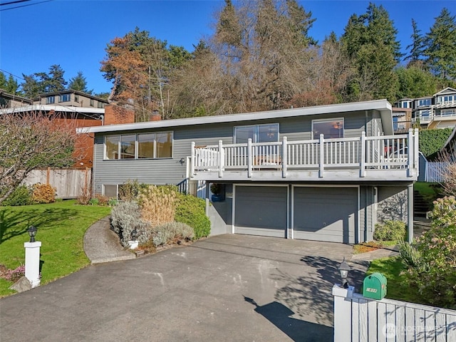 view of front of home featuring driveway, a front yard, a garage, and fence