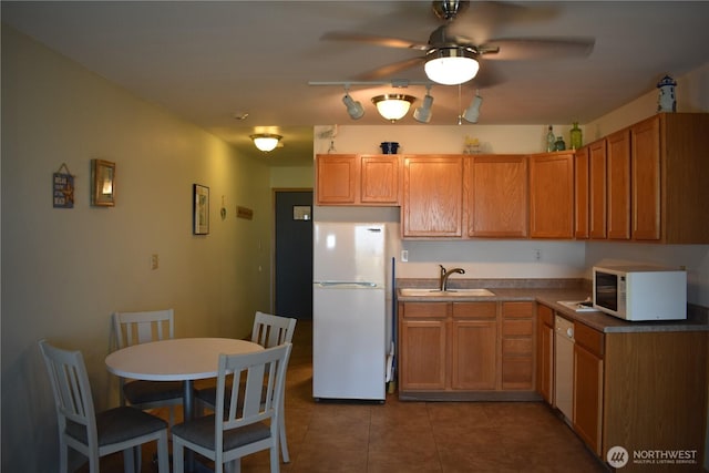 kitchen with dark countertops, ceiling fan, a sink, white appliances, and tile patterned floors