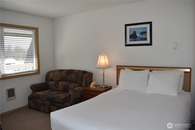 carpeted bedroom with baseboards, a textured ceiling, and heating unit