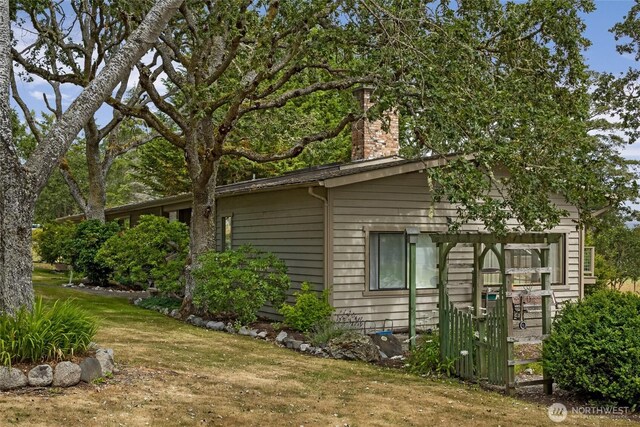 64 Garry Oak Ln, Friday Harbor, WA 98250 - view of home's exterior featuring a lawn and a chimney