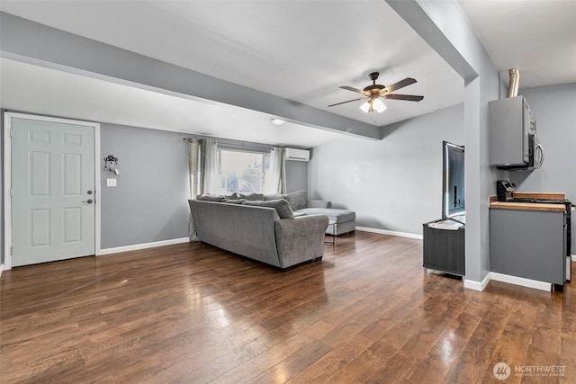 living area featuring a wall unit AC, ceiling fan, baseboards, and dark wood-type flooring