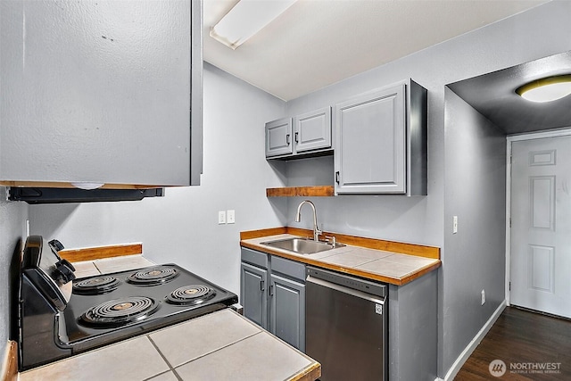 kitchen with black range with electric stovetop, a sink, stainless steel dishwasher, gray cabinets, and tile counters