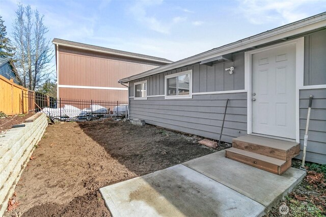 view of side of home with entry steps and fence