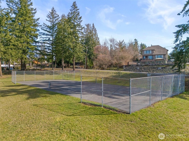 view of sport court with fence and a lawn