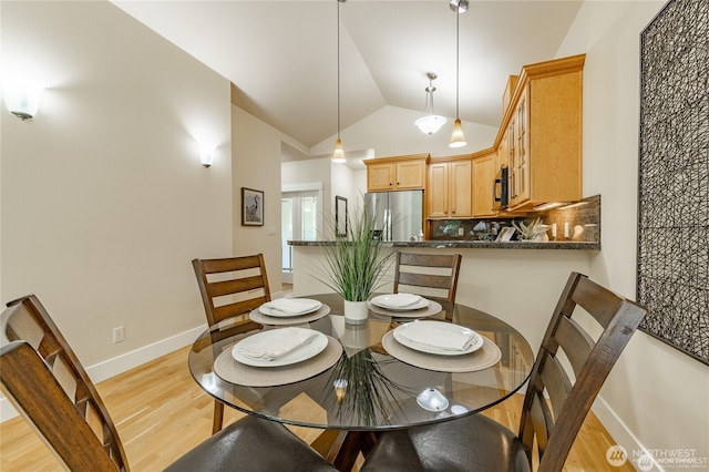 dining room featuring lofted ceiling, baseboards, and light wood-style floors