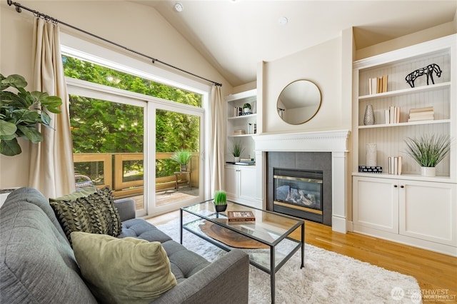 living area featuring light wood-style floors, vaulted ceiling, and a tiled fireplace