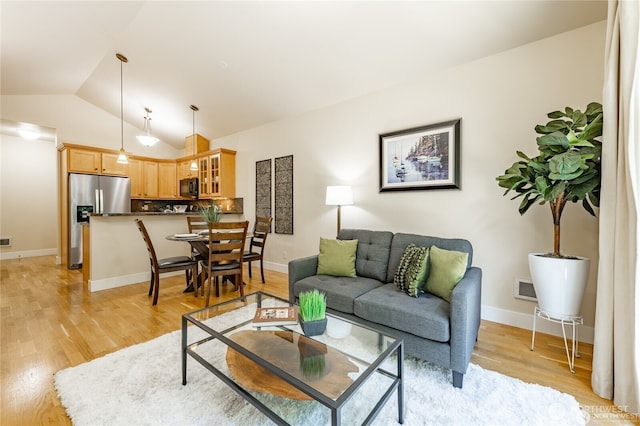 living room featuring vaulted ceiling, light wood-type flooring, and baseboards