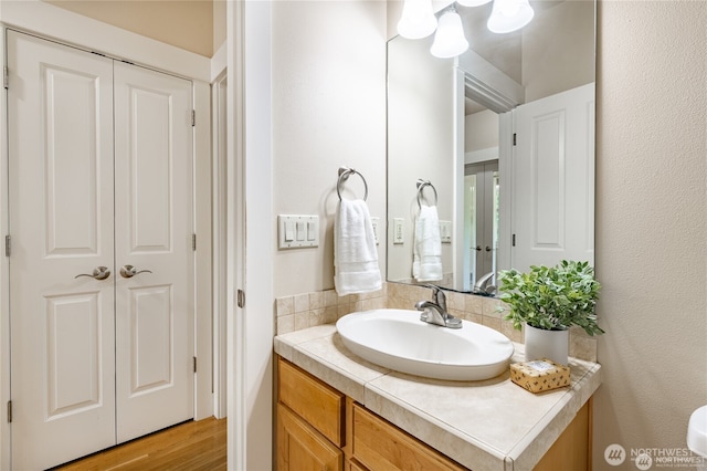 bathroom with a closet, wood finished floors, and vanity