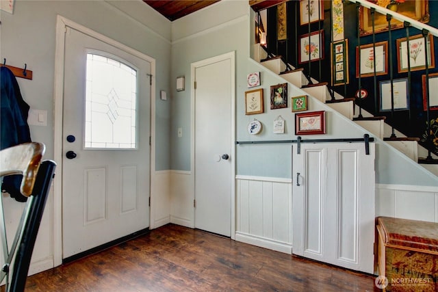 entrance foyer with stairs, dark wood-style flooring, and wainscoting