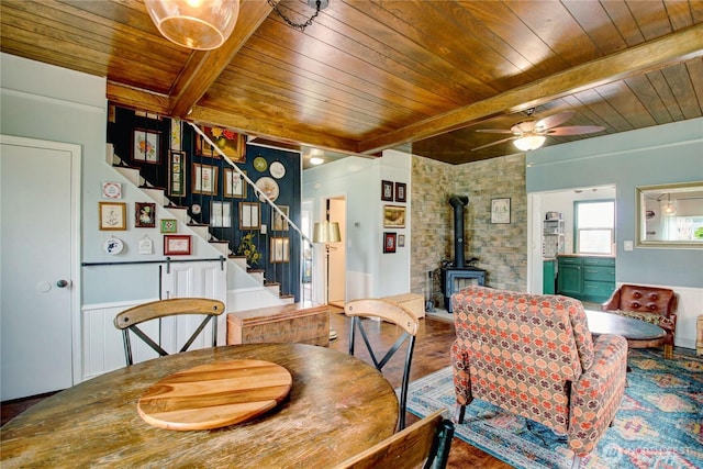 dining room featuring stairs, wooden ceiling, a wood stove, and beam ceiling