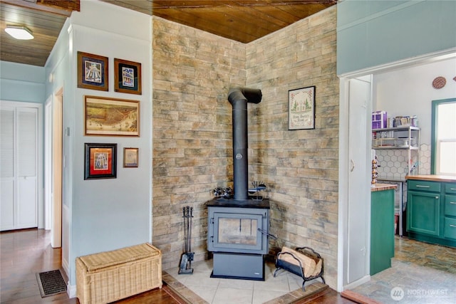 details with visible vents, wooden ceiling, and a wood stove