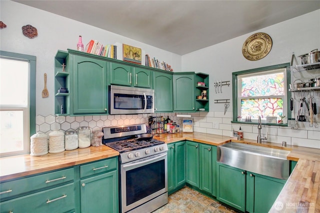 kitchen featuring open shelves, wooden counters, appliances with stainless steel finishes, and a sink