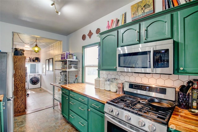 kitchen featuring wooden counters, green cabinetry, washer / clothes dryer, stainless steel appliances, and backsplash