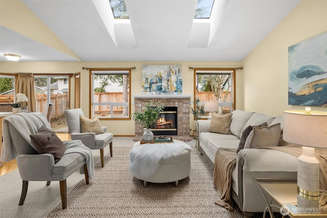 living room featuring a brick fireplace, vaulted ceiling with skylight, and a healthy amount of sunlight