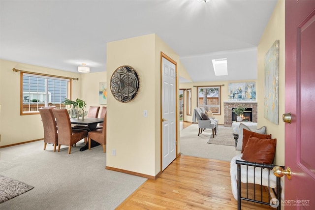 corridor featuring baseboards, light wood finished floors, and light carpet