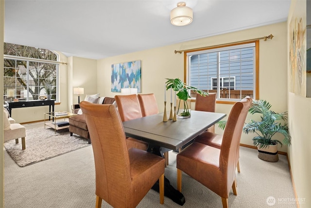 carpeted dining space with a healthy amount of sunlight and baseboards